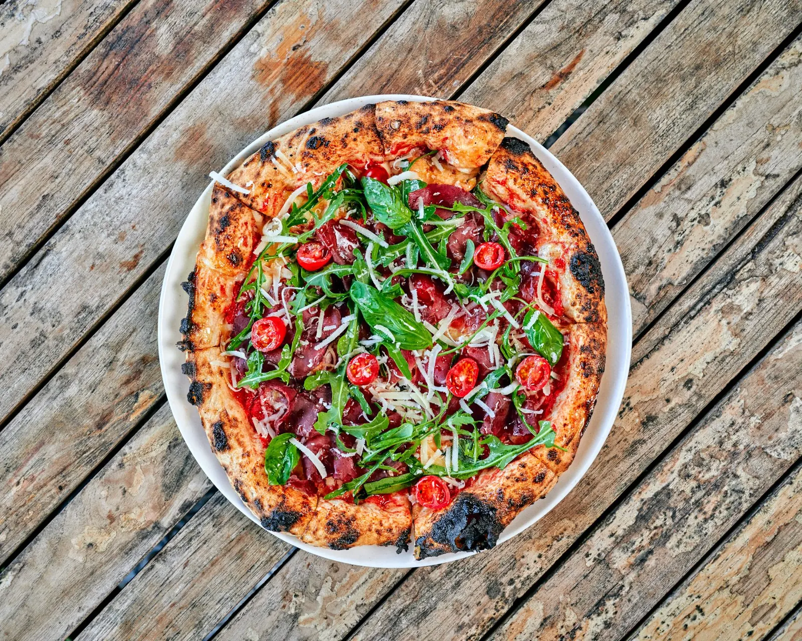 Pizza à la viande séchée, roquette et tomates cerises